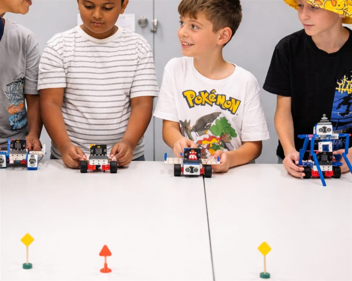 Kids lining up the micro:bit robot rovers they built, ready to race at a ThinkerLab workshop