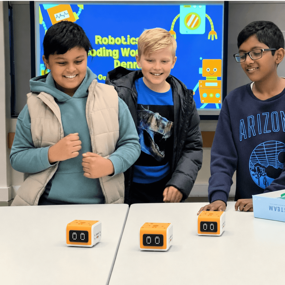 Young children smiling at a ThinkerLab junior robotics and coding class with their coding cube robots